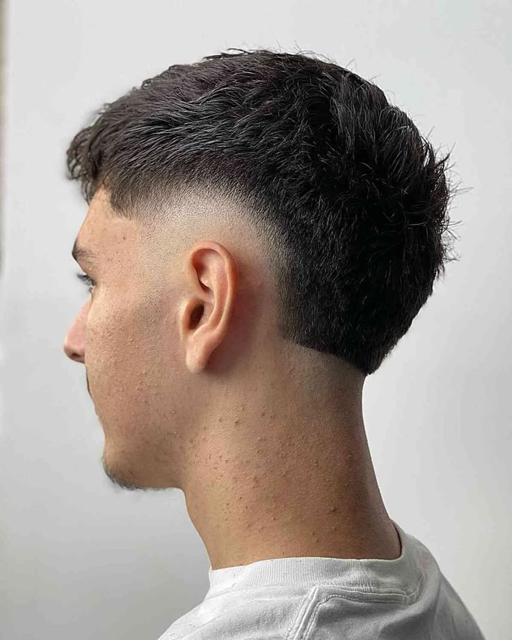 A young man with a drop fade haircut, where the fade curves down behind the ear for a sleek and clean finish.
