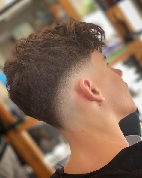 A young man with a sharp skin fade haircut, neatly styled for a modern and fresh look.